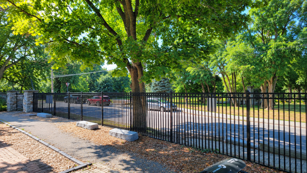 Black aluminum fence dividing a grassy path between modern homes in autumn