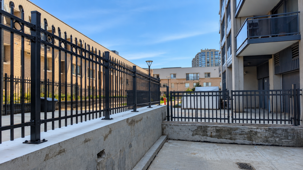 Autumn view of suburban homes with black metal fences and a sidewalk